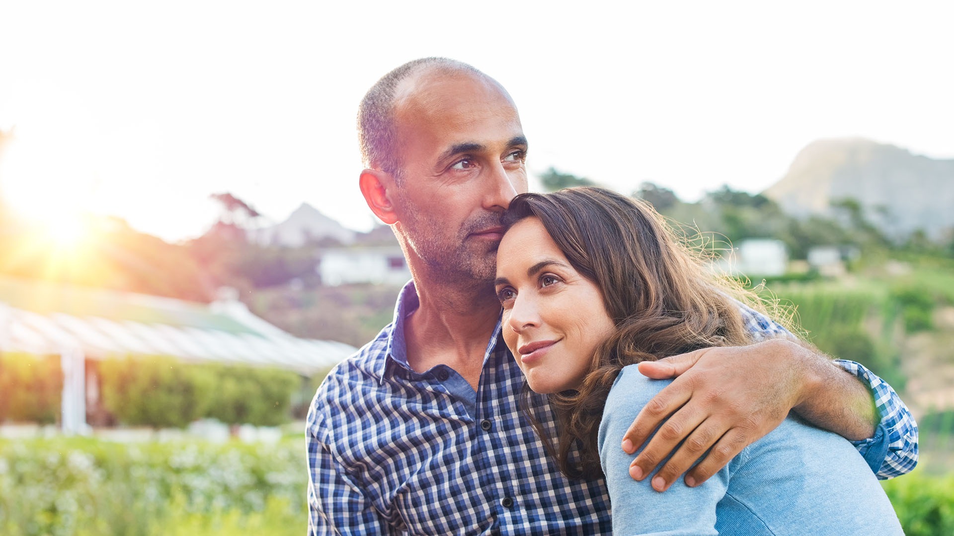 Loving man and happy woman in a spring blooming park. Happy mature couple in love embracing outdoor. Hispanic boyfriend embracing her brunette girlfriend during sunset in a summer day.