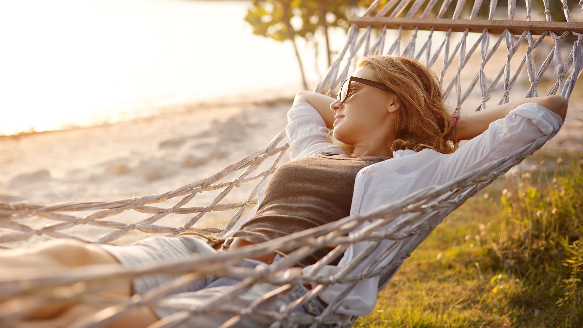 beautiful girl in a hammock on the beach, watching the sunset