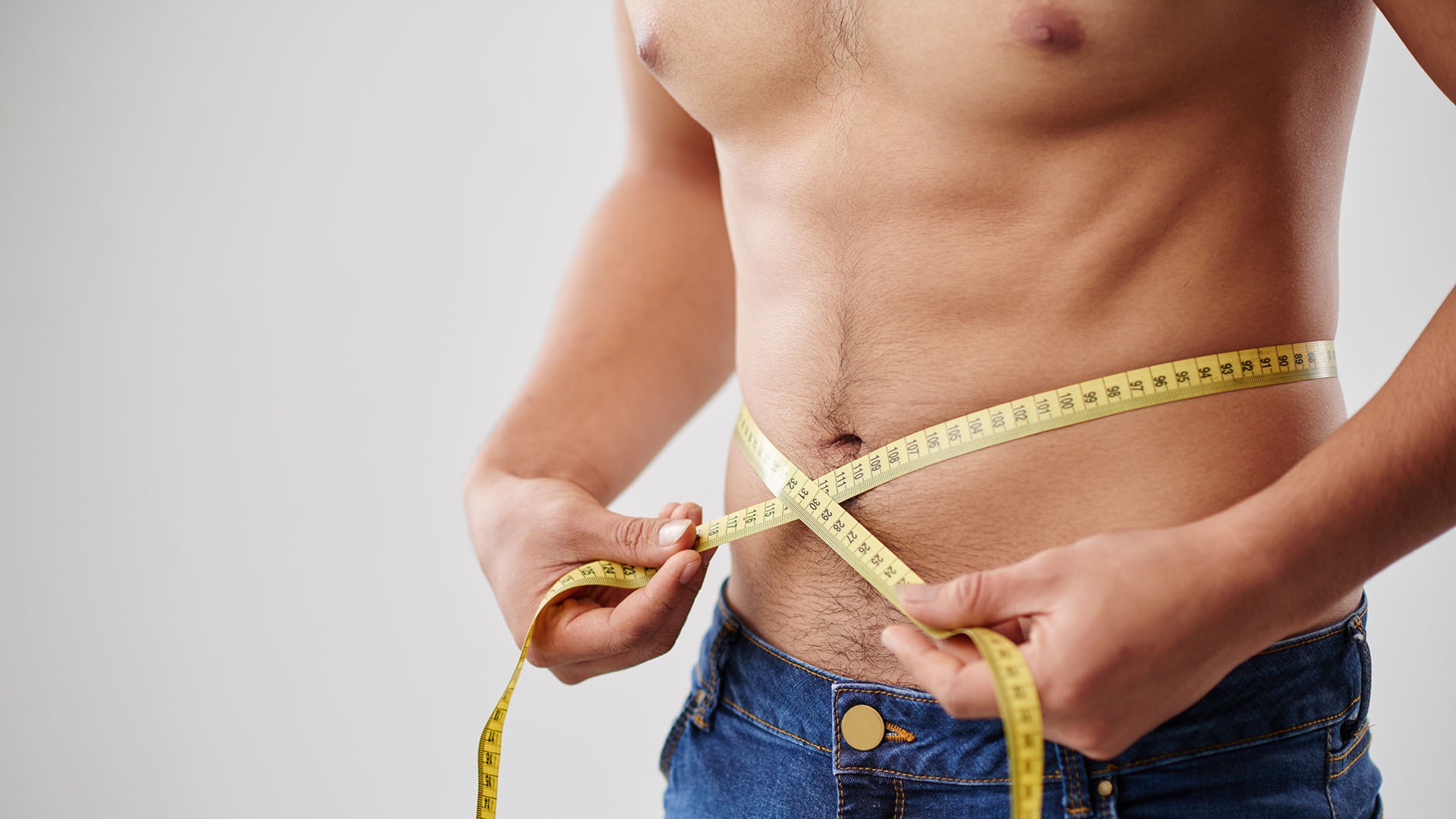 Cropped image on man measuring his waist with tape