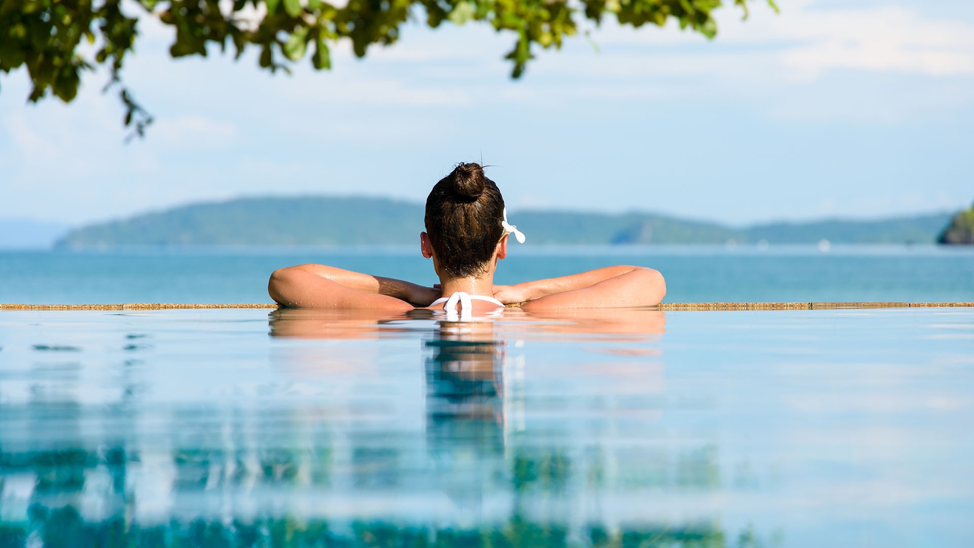 Relax and spa concept. Woman with a flower in hair relaxing in a pool at Krabi, Thailand.
